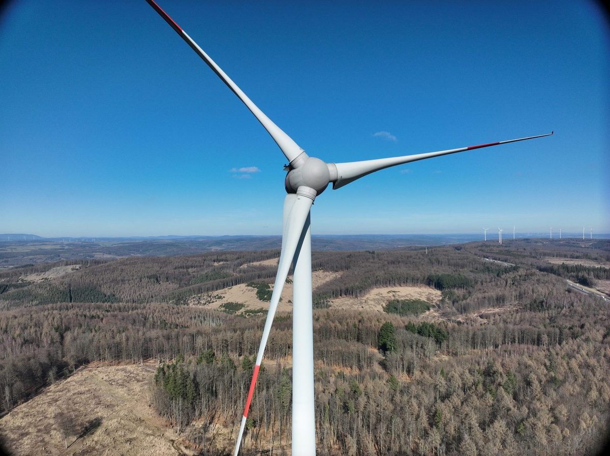 Nabe und Rotorblätter einer Windenergieanlage vor blauem Himmel